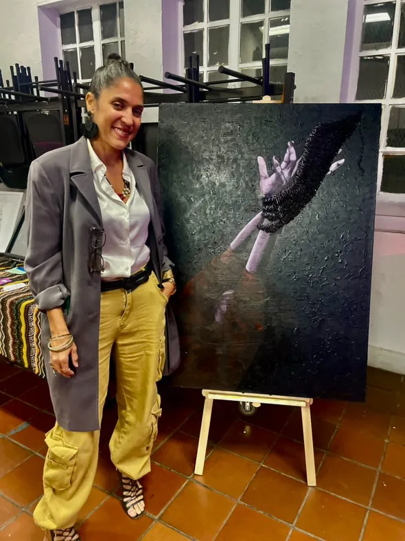 Maryam standing beside The Grab on an easel