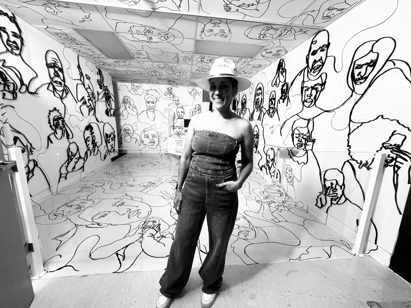 Maryam standing inside a room covered floor to ceiling in her continuous line drawings