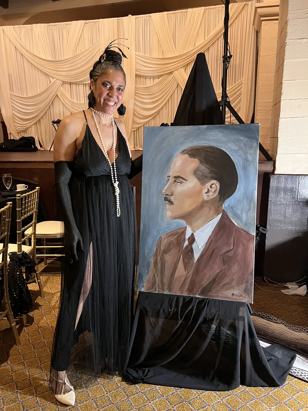 Maryam at the Alpha Phi Alpha gala beside her portrait of a man in a suit and tie