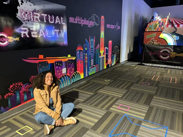 Maryam sitting in front of her neon skyline mural in Chino