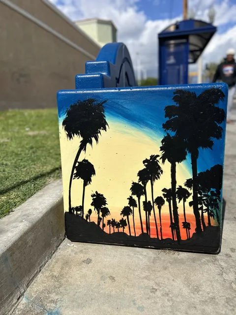 Side of the Colton bench with palm silhouettes on an orange and blue sky
