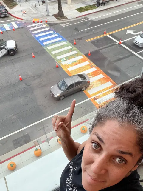 Maryam taking a selfie above her rainbow crosswalk at the Riverside Public Library
