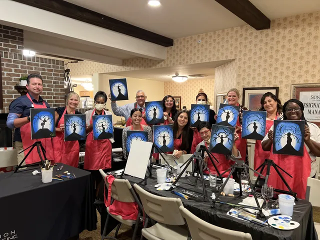 Guests in red aprons holding up their night sky paintings