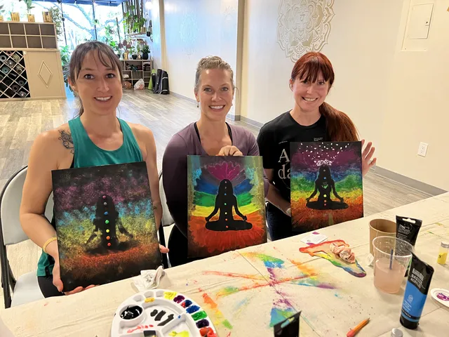Three women holding up their colorful meditation paintings