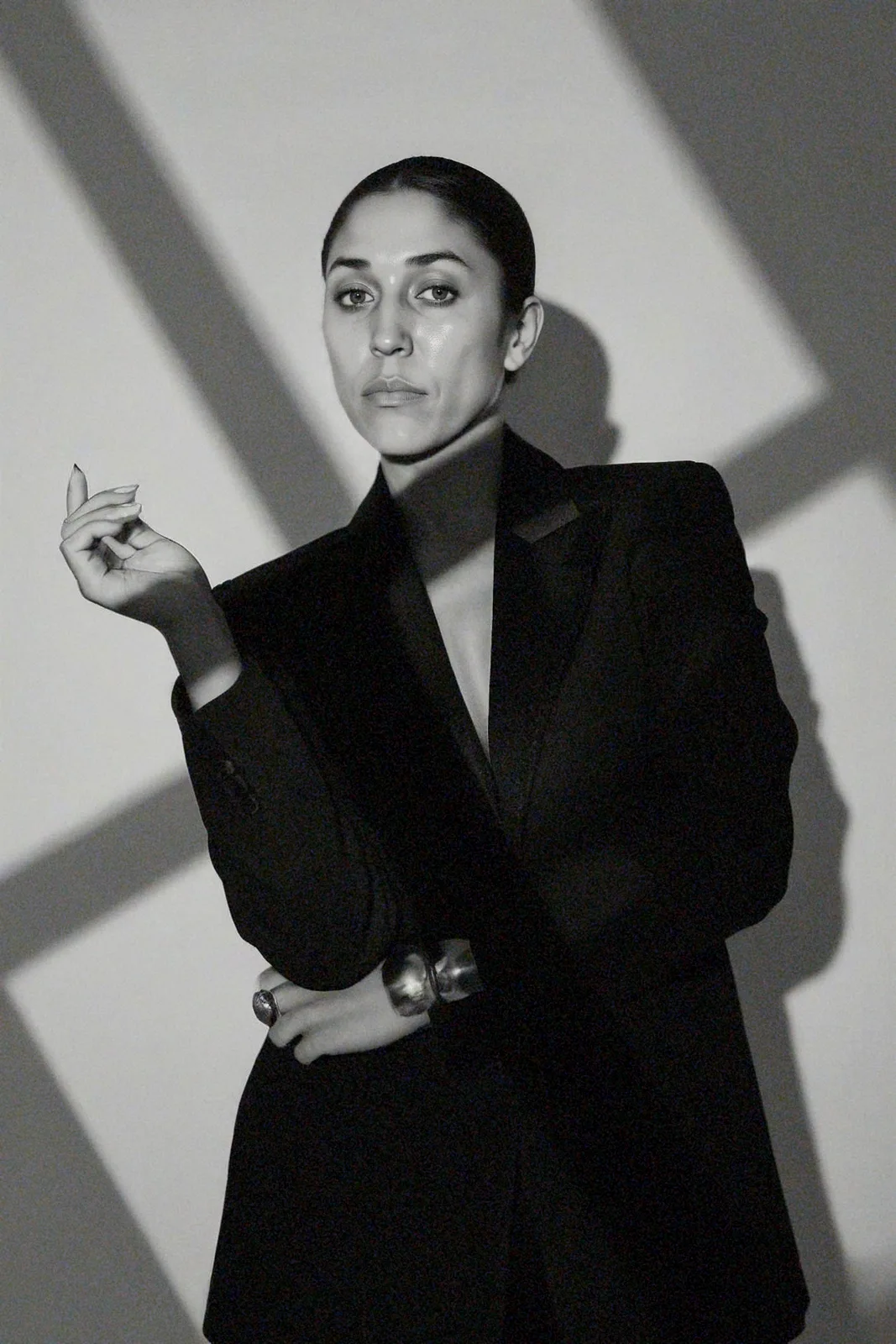 Dr. Maryam Trebeau in a black blazer, hand raised, in dramatic side light